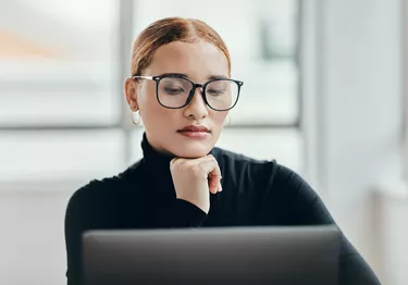 Thinking, solution and laptop business woman working, planning and strategy in office with technology. Mindset, idea and expert entrepreneur reading online report, internet and vision for growth