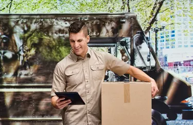One man only / one person / waist up / front view / looking down of 30-39 years old adult handsome people brown hair / short hair caucasian male / young men delivery person / manual worker standing at the delivery van who is delivering / working