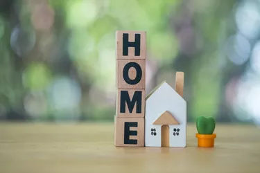 Wooden cubes with the word home placed with home model and miniature cactus. Real estate business