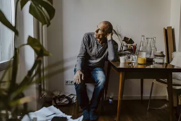 Thoughtful senior man sitting on chair in living room