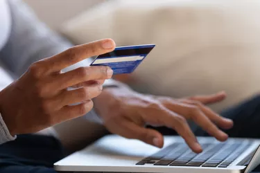 Close up of girl hold bank card and type on laptop