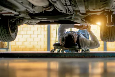 Mechanic lying and working under car at the repair garage
