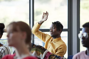Confident student looking away with arm raised