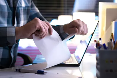 Angry man tearing paper in half home or in modern office at night.