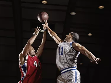Basketball player trying to take basketball from opponent