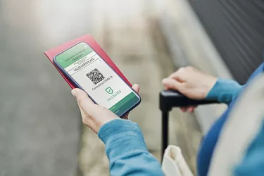 Mid adult woman using a Digital vaccine passport with smart phone in outdoor.