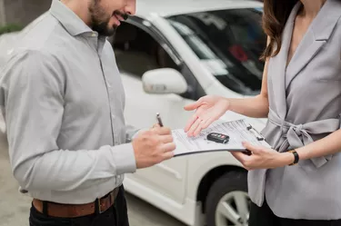 Automotive business, car sale or rental concept : Happy customer with car dealer agent making deal and signing on agreement document contract in auto showroom or car dealer office.