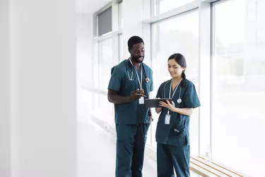 Two doctors in hospital hallway discussing electronic patient record