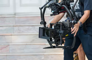 Movie shooting or video production and film crew team with camera equipment. Video camera operator working with equipment. Director of photography with a camera in his hands on the set