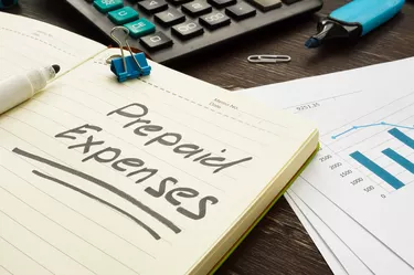 Prepaid expenses sign in the notepad and pile of papers.