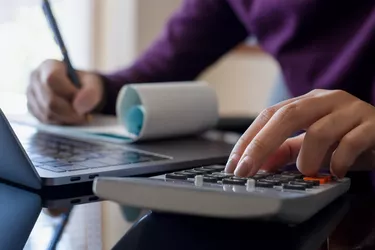 Business woman using calculator and signing cheque, work on laptop computer at office.
