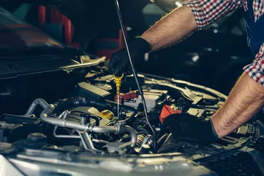 Car mechanic checking oil level in a mechanical workshop