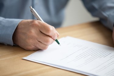 Male hand signing document, senior man putting signature on paper