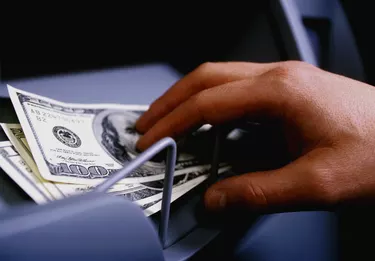 MANS HAND TAKING CASH FROM CASH DISPENSER
