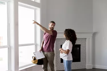 Home inspector points to something outside while talking with homeowner