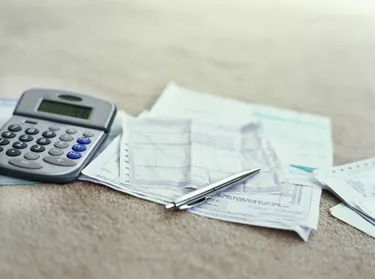 calculator and a ballpoint pen on bills