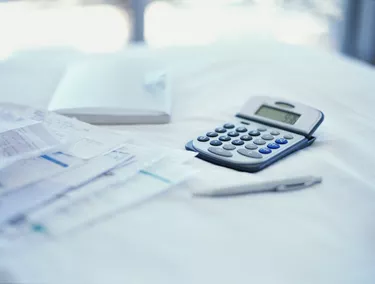 close-up of bills with a calculator and a pen