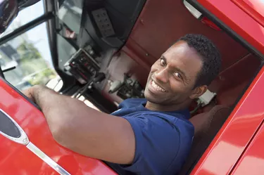 A firefighter sitting in the cab of a fire engine