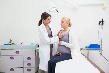Female doctor auscultating a pregnant woman on an examination table