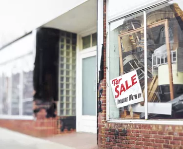 Abandoned Storefront with For Sale Sign and Stacks of Furniture