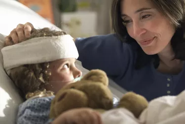 a caucasain mother visits and consoles her young child as she lays recovering in the hospital