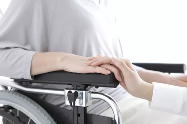 Daughter holding the hand of her mother in a wheelchair