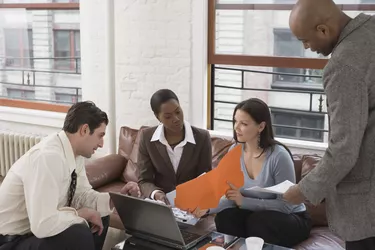 Businesspeople looking at documents and laptop