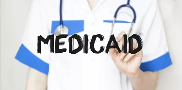 Doctor writing text Medicaid with marker