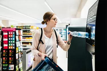 Young Woman Recycling Bottles At The Supermarket