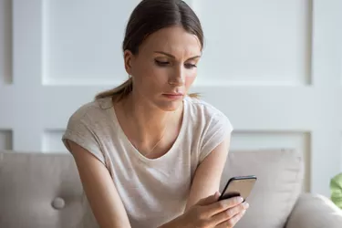 Thoughtful young woman looking at cellphone screen.