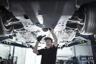 Engineer working underneath car on lift in car service centre