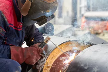 Construction worker arc welding the metal pipe.